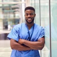 Male nurse posed and leaning against a glass wall.