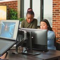 Two people sharing a computer and discussing a design project.