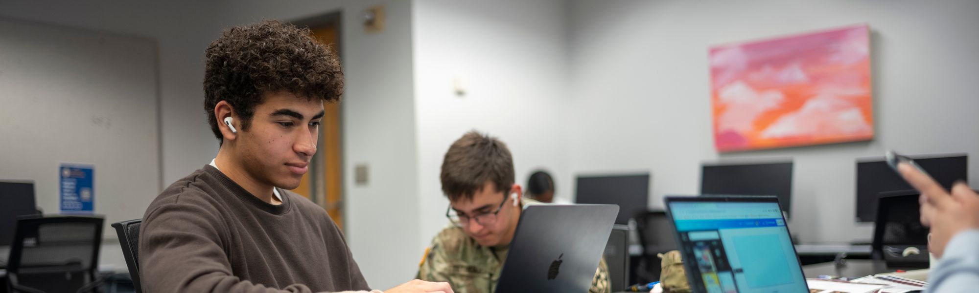 Student on their laptop seated at table with peers