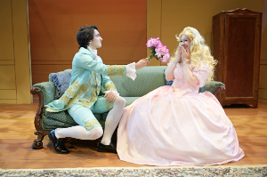 man offering flowers to a woman as they sit on a couch.