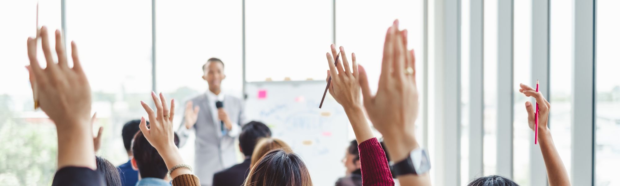 Business professionals raising their hands during a training.