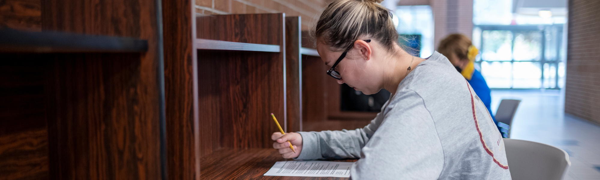 A female student taking notes at a desk.